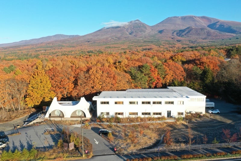 紅葉の森と浅間山を背にした still の建物を上空から